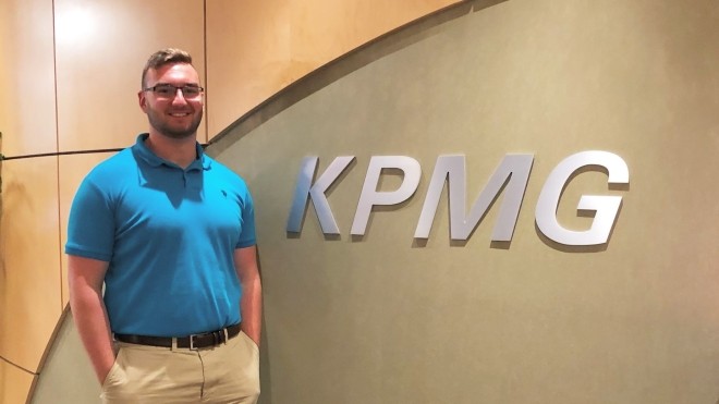 Co-op student standing in front of KPMG logo