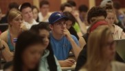 Close up of a student sitting in class, while there are other students sitting in the background.